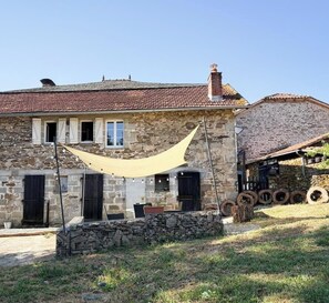 A stone house with a tiled roof, a hammock, and a stack of tires. - La Parenthèse - SOUSCEYRAC IN QUERCY (SOUSCEYRAC EN QUERCY)