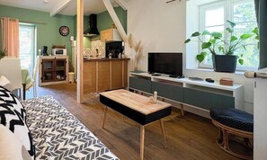 A compact living space with a sofa, a dining table, a TV, and a kitchen area. - La Parenthèse - SOUSCEYRAC IN QUERCY (SOUSCEYRAC EN QUERCY)