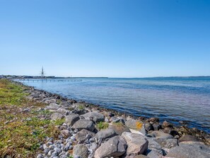A coastal scene with a rocky shoreline, calm water, and a distant ship. - "Svane" - 70m from the sea by Interhome (Ebeltoft)