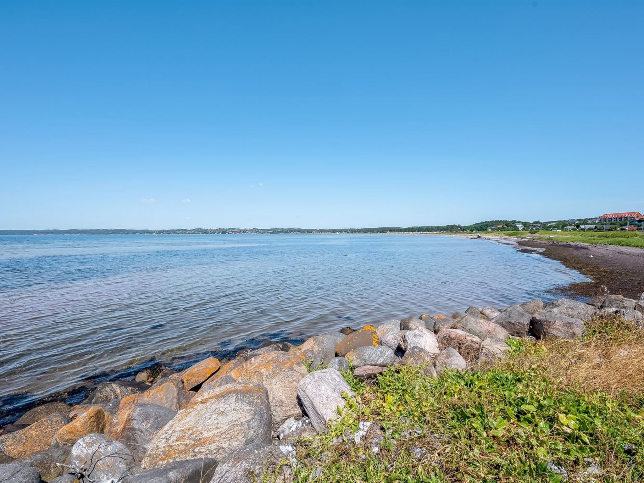 A coastal landscape with a rocky shoreline and calm water.