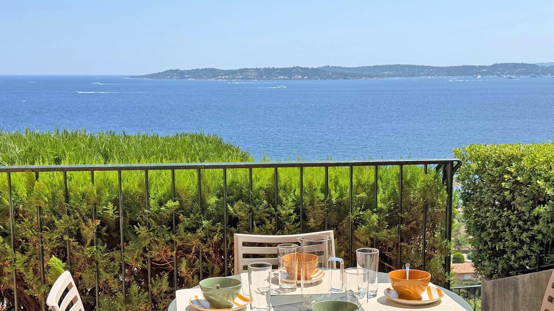 Mesa lista para comer con vista al mar y colinas al fondo.