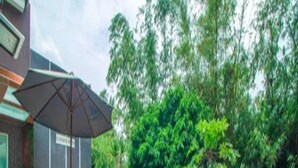 A swimming pool with lounge chairs and an umbrella, surrounded by greenery. - Cozzy Villa Dewata (batu)