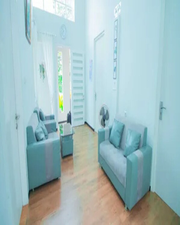 A living room with two sofas, a coffee table, and a fan. - Cozzy Villa Dewata (batu)