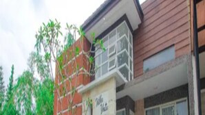A building with a sign that reads 'Villa Yate.' There are two motorcycles parked in front. - Cozzy Villa Dewata (batu)