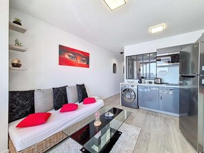 Ein modernes Wohnzimmer mit einer Couch, einem Glastisch und einem roten Gemälde an der Wand.