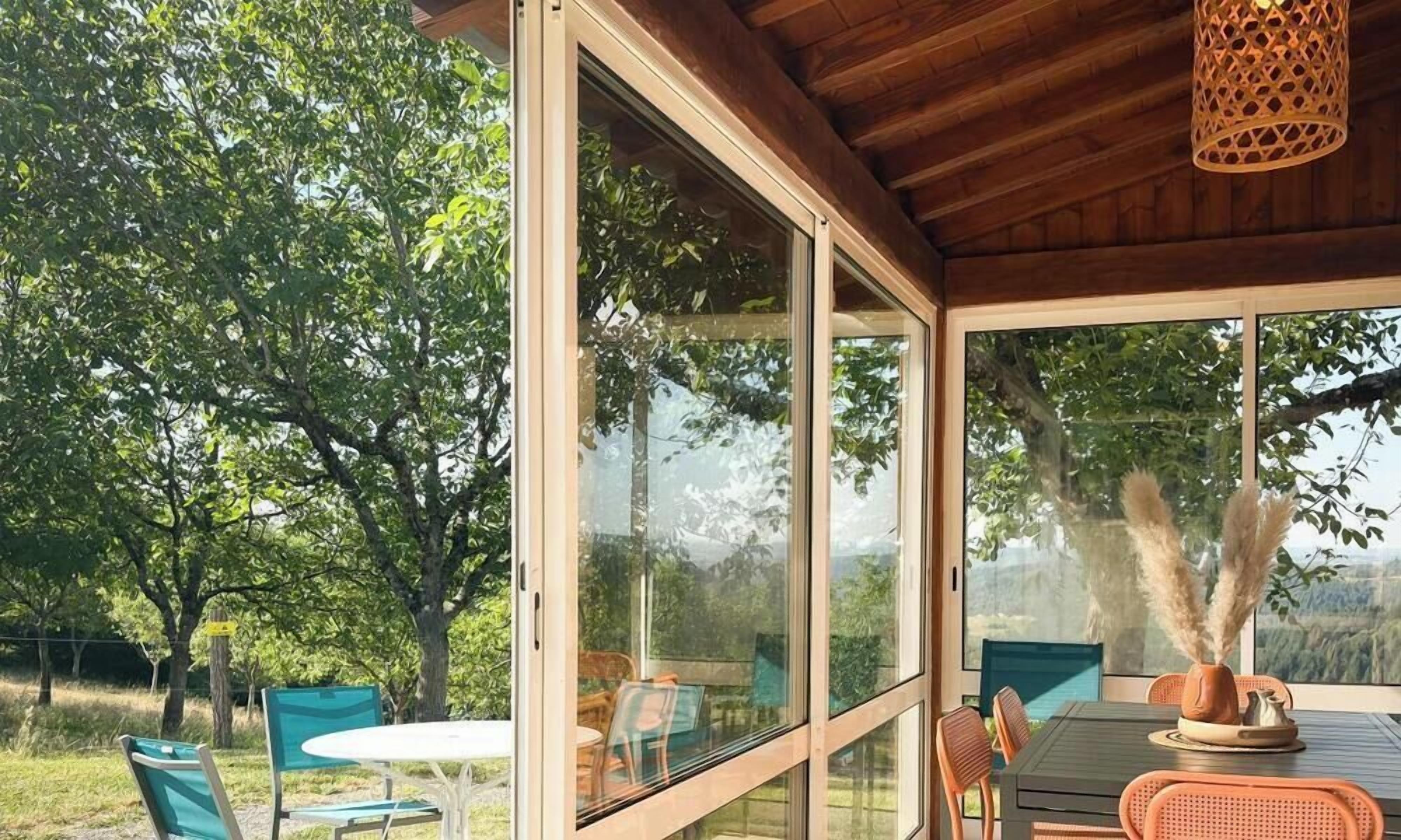 A covered outdoor dining area with glass walls, chairs, and a table.