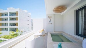Een balkon met een zwembad, witte meubels en uitzicht op andere gebouwen.
