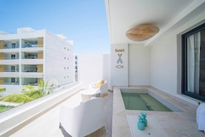 Ein Balkon mit Pool, weißen Möbeln und Blick auf andere Gebäude.