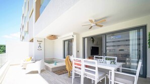 Een modern balkon buiten met een eettafel, stoelen, een klein zwembad en een plafondventilator.