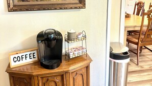 Ein Holzschrank mit einer Kaffeemaschine, einem Schild mit der Aufschrift 'COFFEE' und einem Mülleimer.