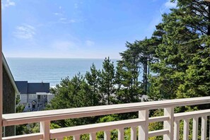 A balcony with a view of the ocean and dense greenery. - Ocean Views, Hot Tub, Fireplaces & Luxury Finishes, Chef's Kitchen, Community Pool, EV Charger, BBQ (Lincoln City)
