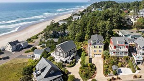 A coastal residential area with houses, a beach, and a forested hillside. - Ocean Views, Hot Tub, Fireplaces & Luxury Finishes, Chef's Kitchen, Community Pool, EV Charger, BBQ (Lincoln City)