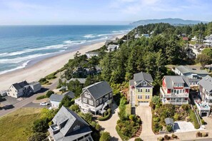 A coastal residential area with houses, a beach, and a forested hillside. - Ocean Views, Hot Tub, Fireplaces & Luxury Finishes, Chef's Kitchen, Community Pool, EV Charger, BBQ (Lincoln City)