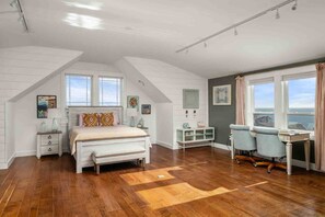 A bedroom with a bed, bedside tables, a desk, and a chair. There are windows and a view of the sea. - Ocean Views, Hot Tub, Fireplaces & Luxury Finishes, Chef's Kitchen, Community Pool, EV Charger, BBQ (Lincoln City)