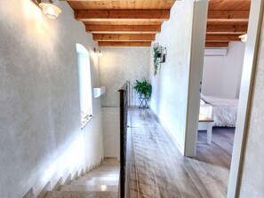 A narrow hallway with wooden beams, a staircase, and a bed in the background. - Vacation home Trošti by Interhome (Barban)