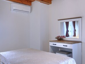 A bedroom with a bed, a dresser, a mirror, and an air conditioning unit. - Vacation home Trošti by Interhome (Barban)
