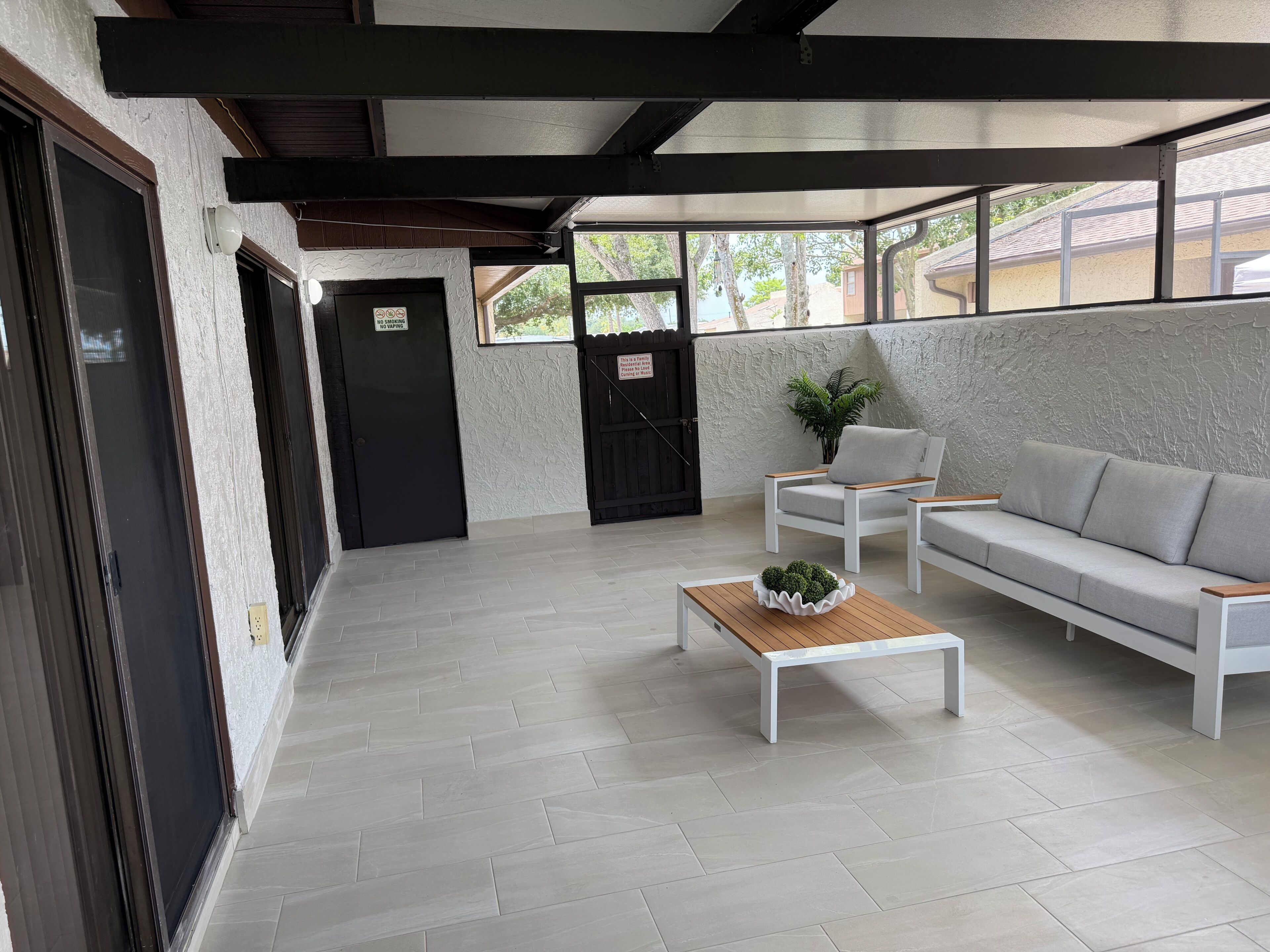 A modern interior with a sofa, a small table with a plant, and a door with a no-smoking sign.