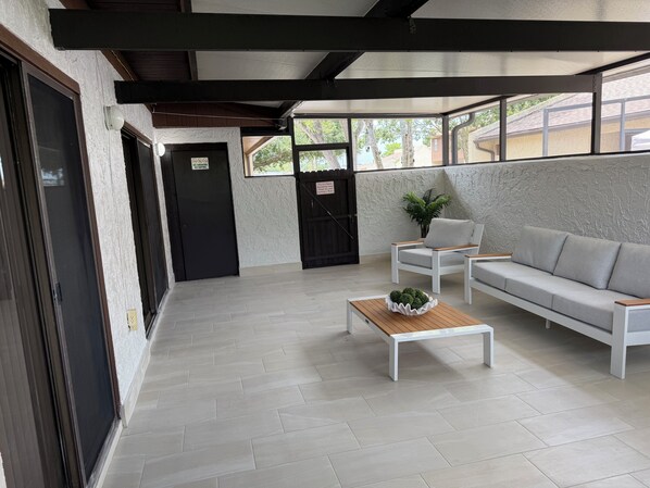 A modern interior with a sofa, a small table with a plant, and a door with a no-smoking sign.