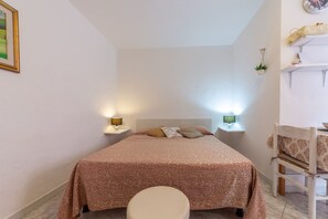 Ein Schlafzimmer mit einem Bett, Nachttischen, Lampen, einem Sessel und einer Wanduhr.