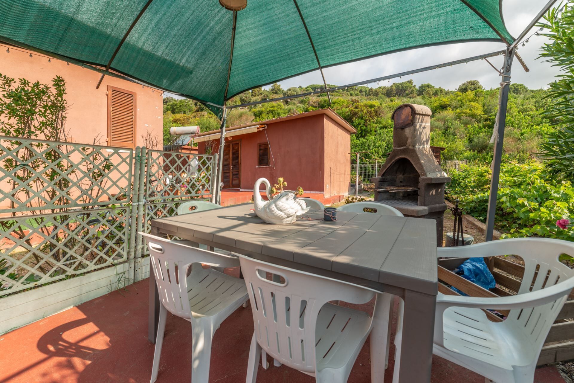 An outdoor patio with a table, chairs, a swan sculpture, and a stone oven.