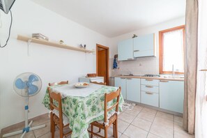 A compact kitchen with a dining table, chairs, and a fan. - APPARTAMENTI I LIMONI - APPARTAMENTI I LIMONI - BILO 4 (Campo nell'Elba)