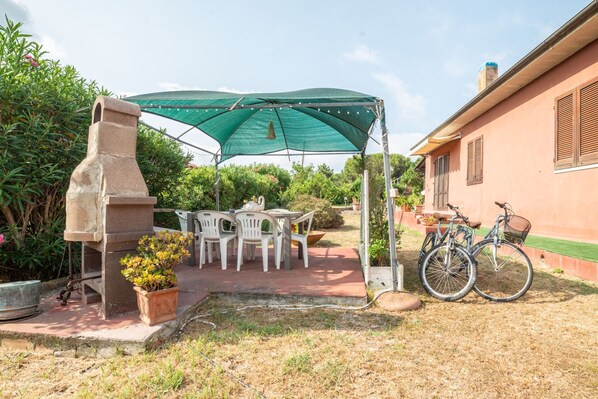 Ein Patio mit Steingrill, Gartenmöbeln und Fahrrädern.