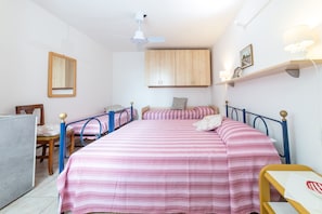 A bedroom with two single beds, a desk, a chair, a ceiling fan, and a wall-mounted shelf with a lamp. - APPARTAMENTI I LIMONI - APPARTAMENTI I LIMONI - BILO 4 (Campo nell'Elba)