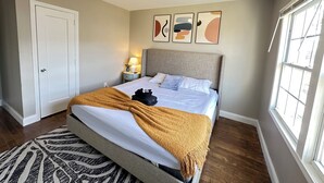 A bedroom with a bed, bedside table, lamp, artwork, and a window. - 1BR Business Suite with Parking Near Downtown Birmingham (Birmingham)