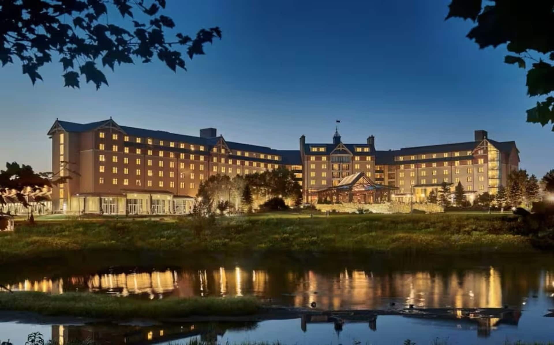 A large hotel with multiple buildings, a central courtyard, and a body of water reflecting the structures.