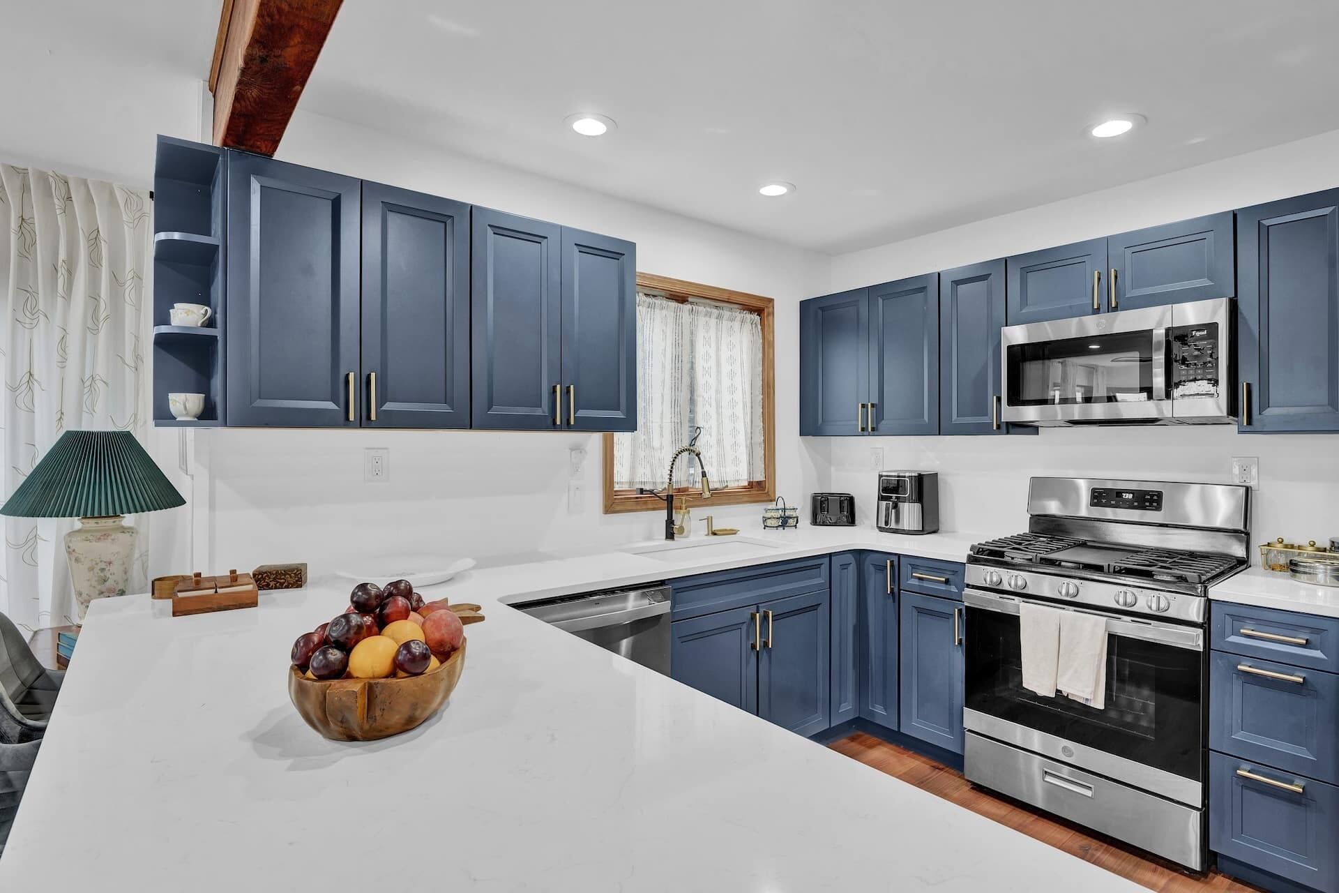 Una cocina moderna con armarios azules, una estufa de acero inoxidable y un microondas.