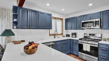 Una cocina moderna con armarios azules, una estufa de acero inoxidable y un microondas.