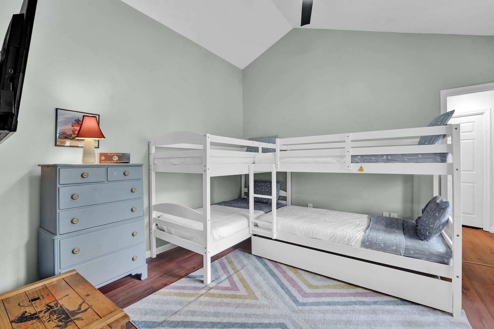A bunk bed room with a dresser and a lamp.