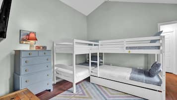 A bunk bed room with a dresser and a lamp.