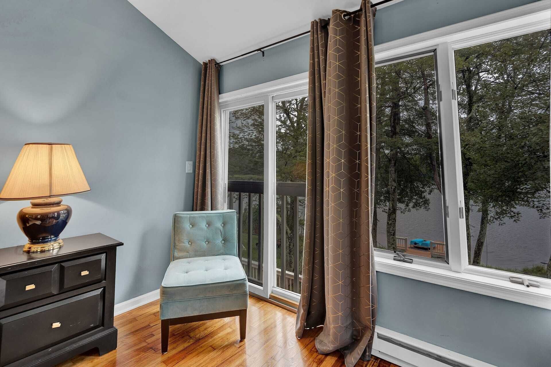 Una habitación con vista al agua, una silla, una lámpara y un aparador.