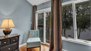 Una habitación con vista al agua, una silla, una lámpara y un aparador.