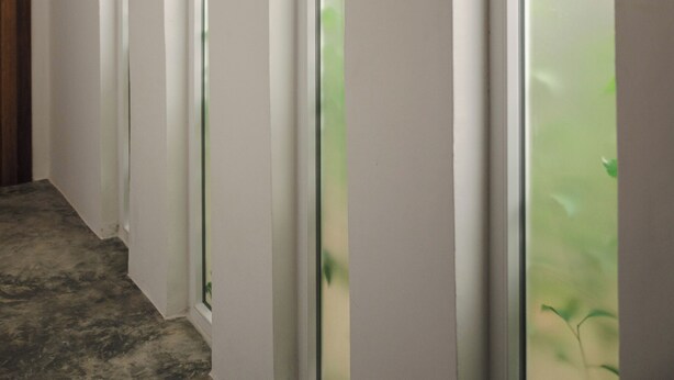 Un couloir avec une porte en bois sur la gauche, qui donne sur une pièce dotée d’une grande fenêtre.
