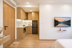 A compact hotel room with a kitchenette, a bed, and a wall-mounted TV. - BB Homes Dao Tan near Lotte (Hanoi)