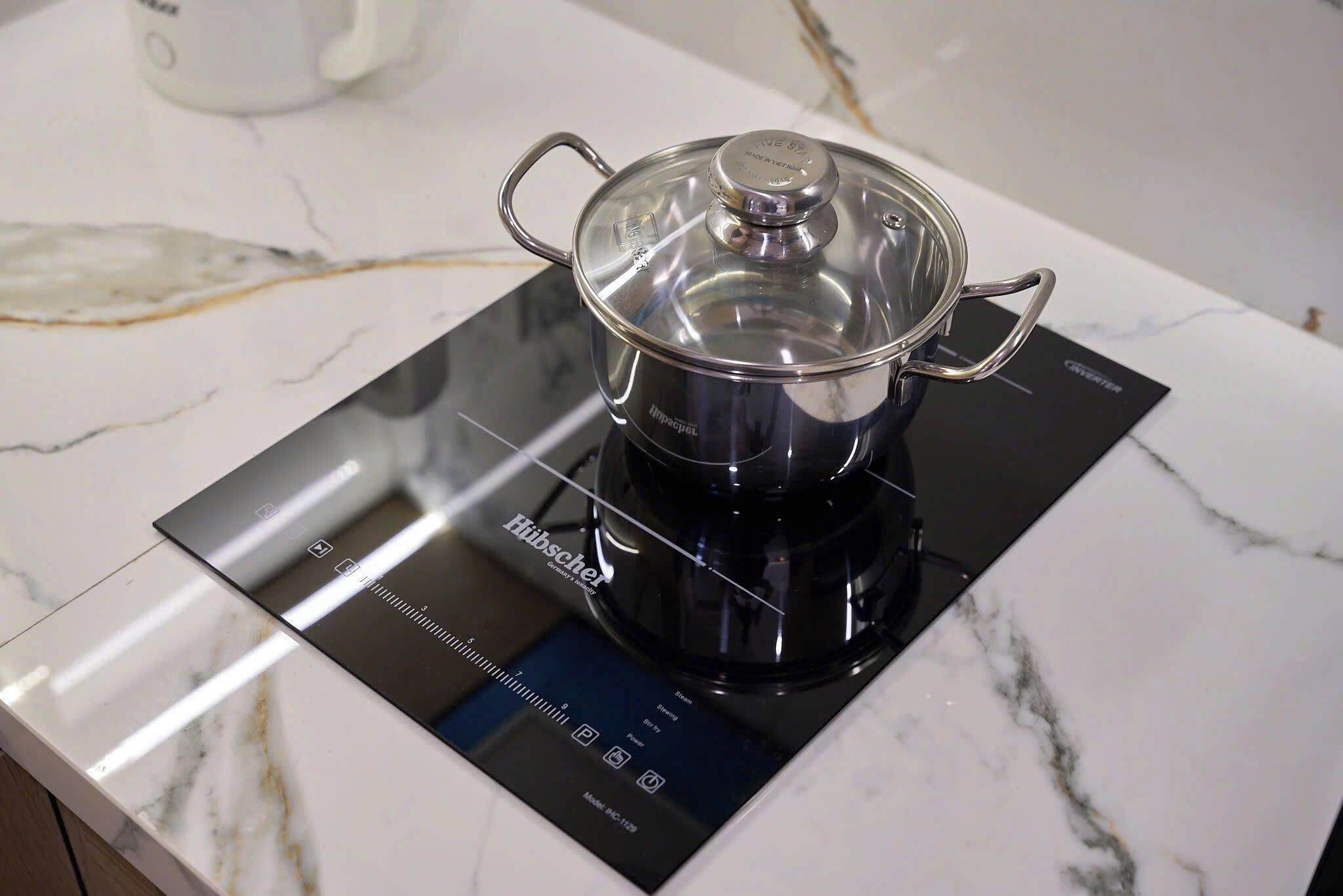 A kitchen with a modern induction cooktop and a pot on it.