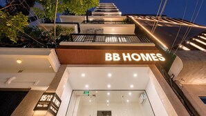 Un edificio comercial con un cartel llamativo de 'BB HOMES', entrada de vidrio y una escalera que conduce a los pisos superiores.