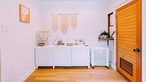 A compact kitchen with white cabinetry, a countertop with various appliances, and a wooden door. - Stylish Hakuba Whitegrove Sauna Chalet (Hakuba)