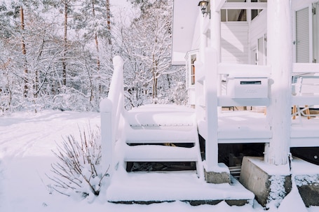 A snow-covered wooden staircase leading to a white building with a porch.