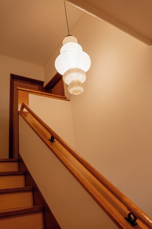 A staircase with wooden handrails and a hanging light fixture. - Stylish Hakuba Whitegrove Sauna Chalet (Hakuba)