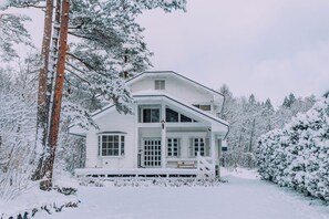 A two-story house with a porch, surrounded by snow-covered trees. - Stylish Hakuba Whitegrove Sauna Chalet (Hakuba)