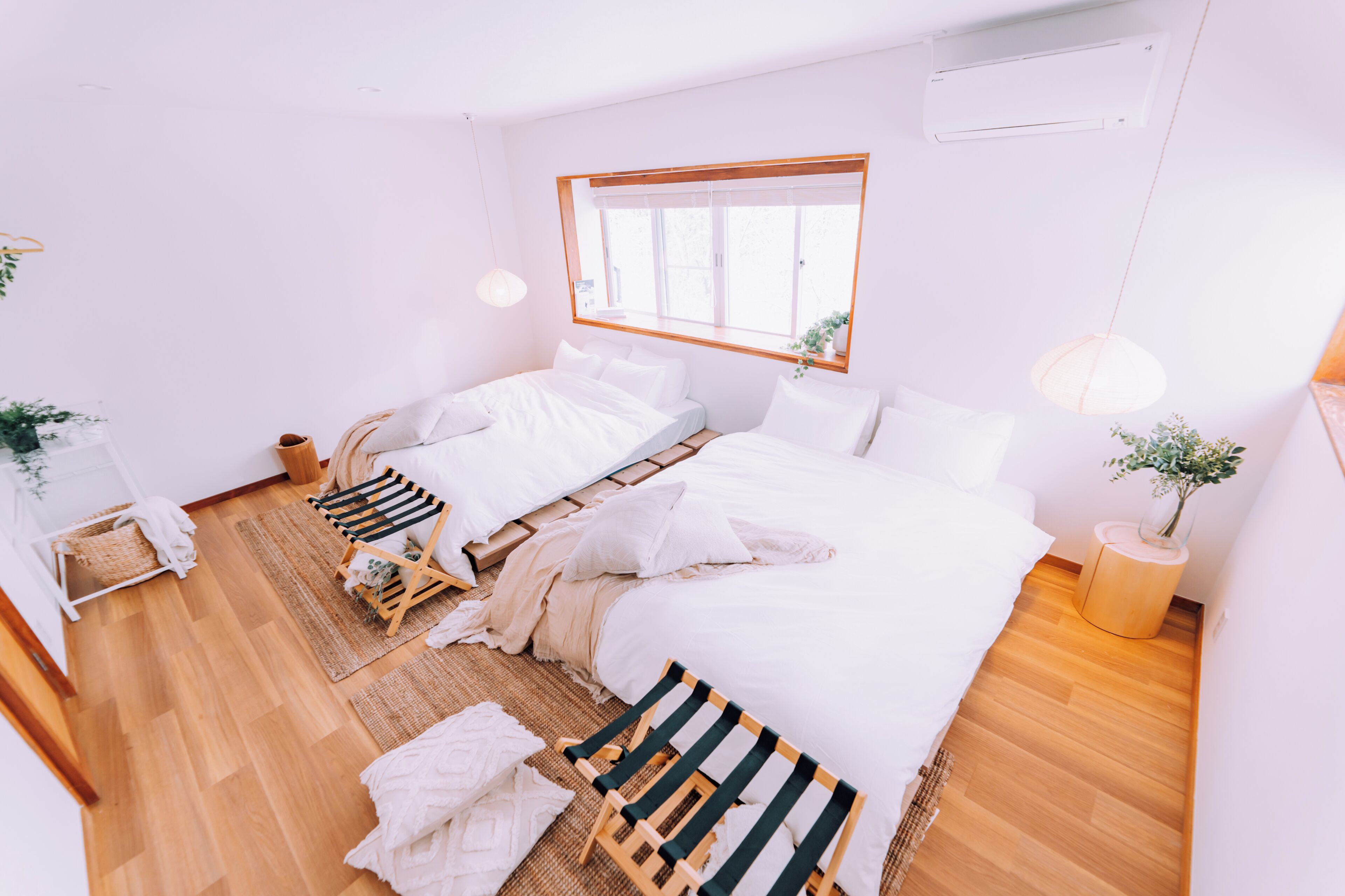 Ein modernes Schlafzimmer mit zwei Betten, einem großen Fenster und Holzboden.