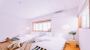 A modern bedroom with a large bed, a wooden chair, a small side table, and a window with a view. - Stylish Hakuba Whitegrove Sauna Chalet (Hakuba)