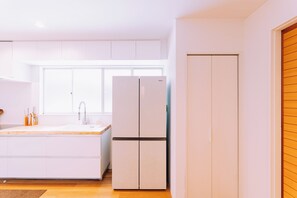 Uma cozinha moderna com armários brancos, uma geladeira de portas duplas e uma janela sobre a pia.