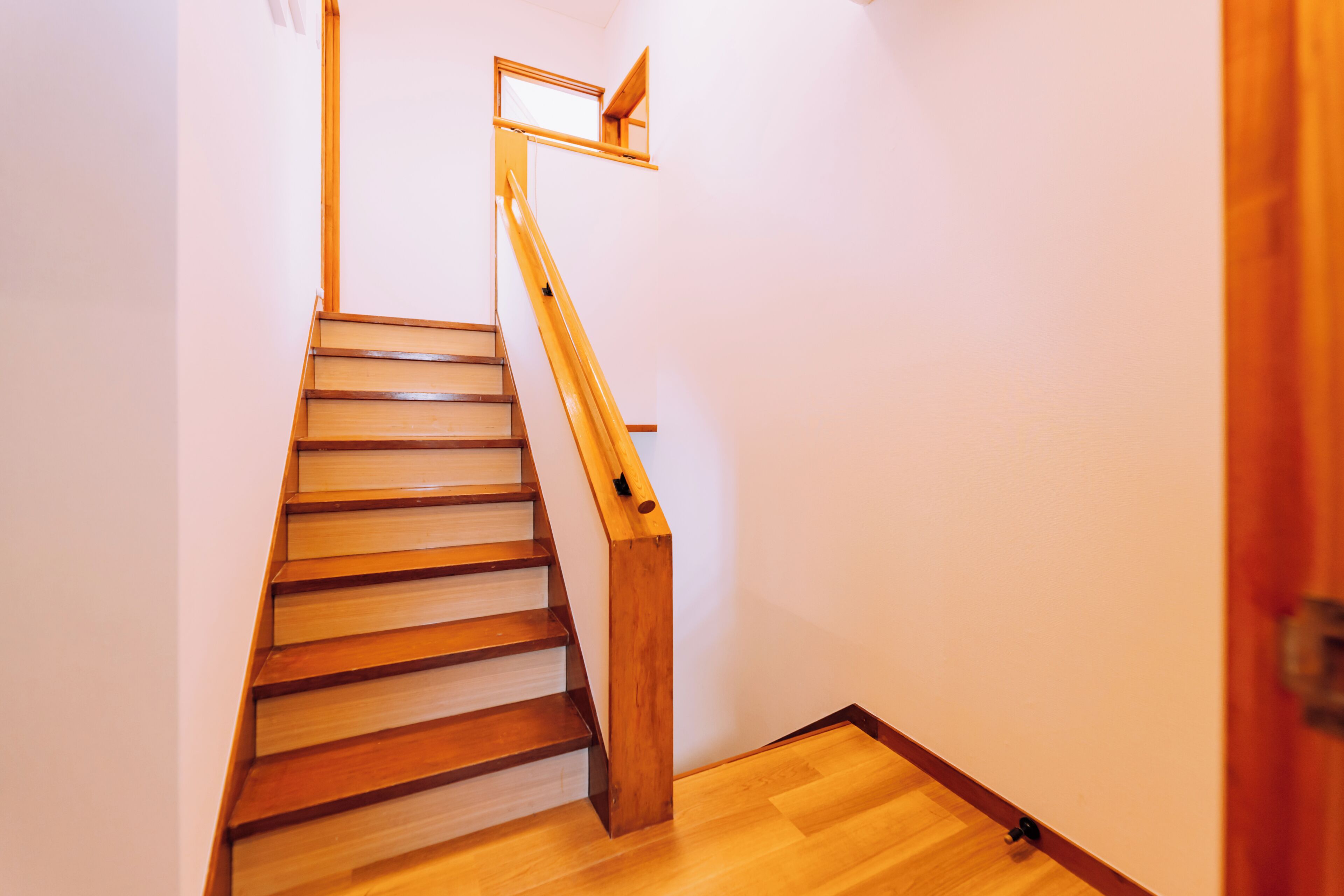 A wooden staircase with a handrail and a landing.