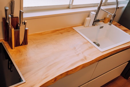 A kitchen with a wooden countertop, a sink, and a window above.