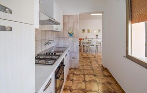 A narrow kitchen with a gas stove, white cabinets, and a tiled floor. - Amazing home in Ispica with WiFi (Ispica)
