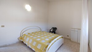 A bedroom with a bed, a chair, a small table, and a wardrobe. - Amazing home in Ispica with WiFi (Ispica)